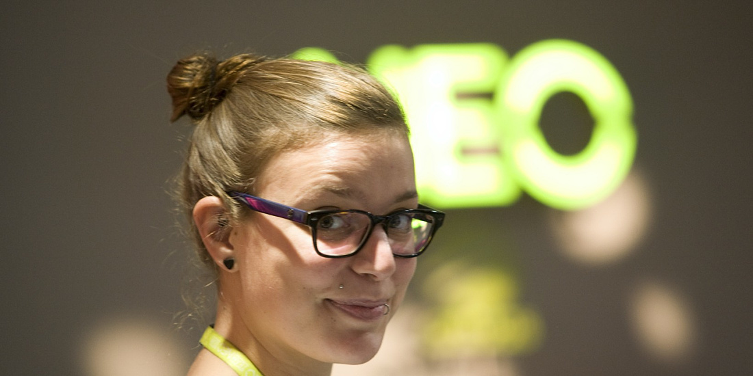 Woman in front of illuminated Adidas NEO logo, highlighting dynamic LED lighting in the Cologne store.
