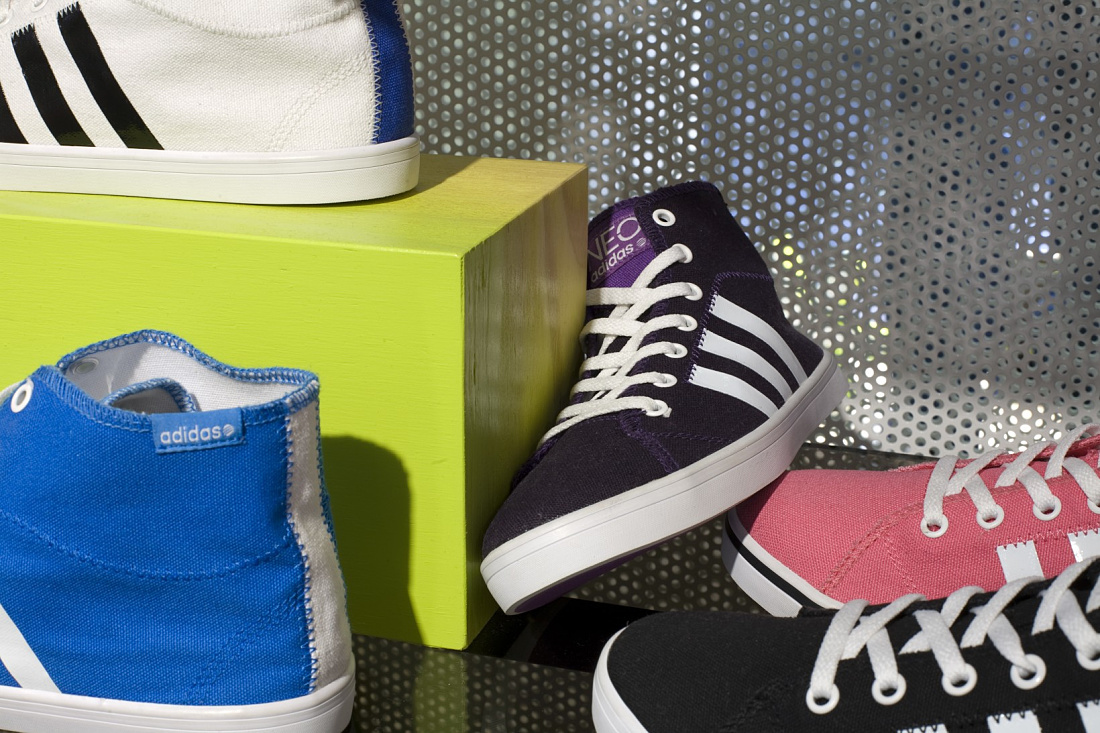 Colorful Adidas NEO shoes displayed with dynamic LED lighting in the Cologne store.