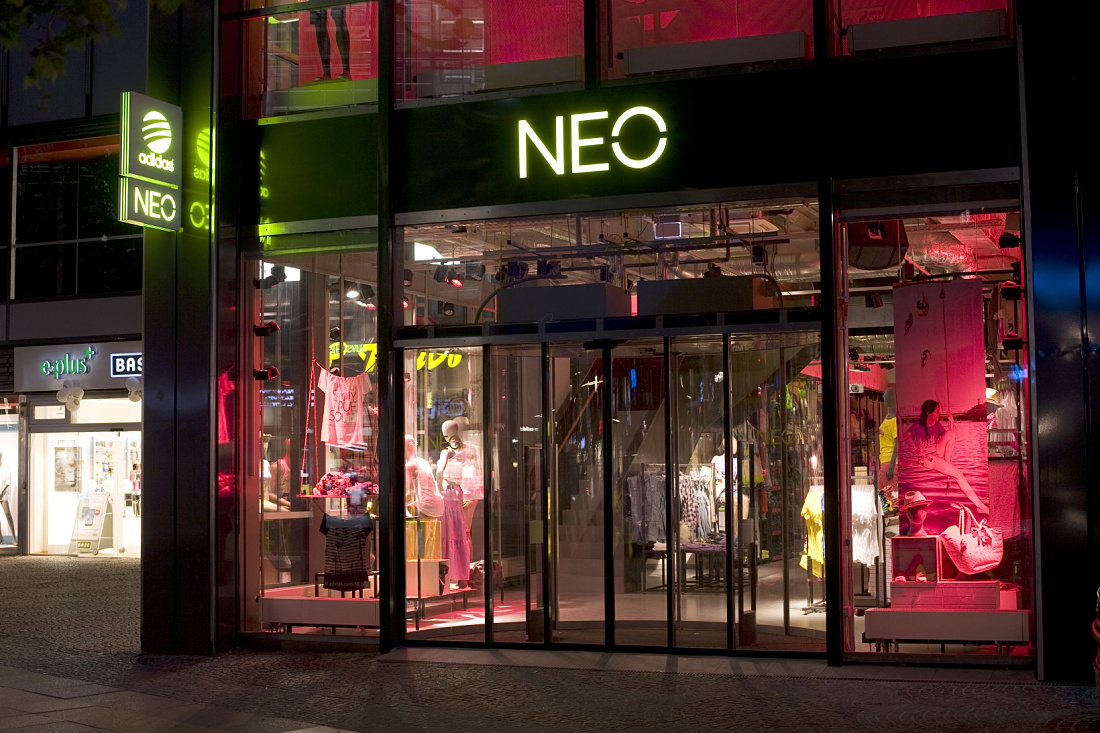 Adidas NEO store on Tauentzienstrasse, dynamically lit with ERCO Optec spotlights and colored accents.