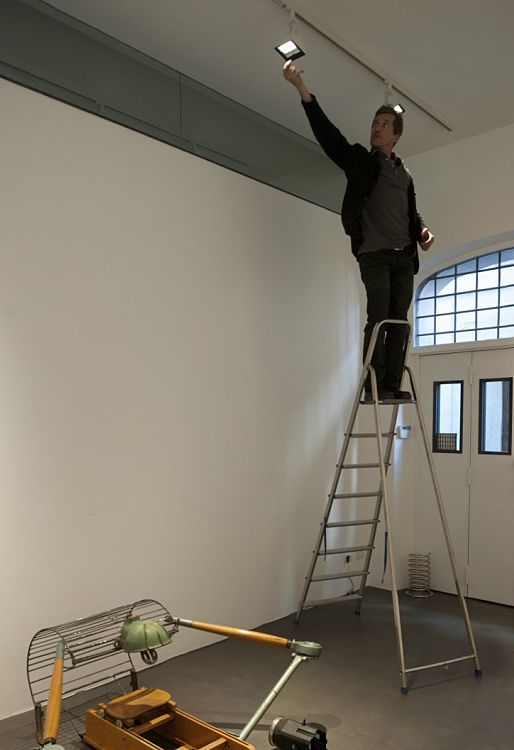 Man adjusts a Light Board spotlight on a ladder in the Anna Marra Contemporanea Gallery.