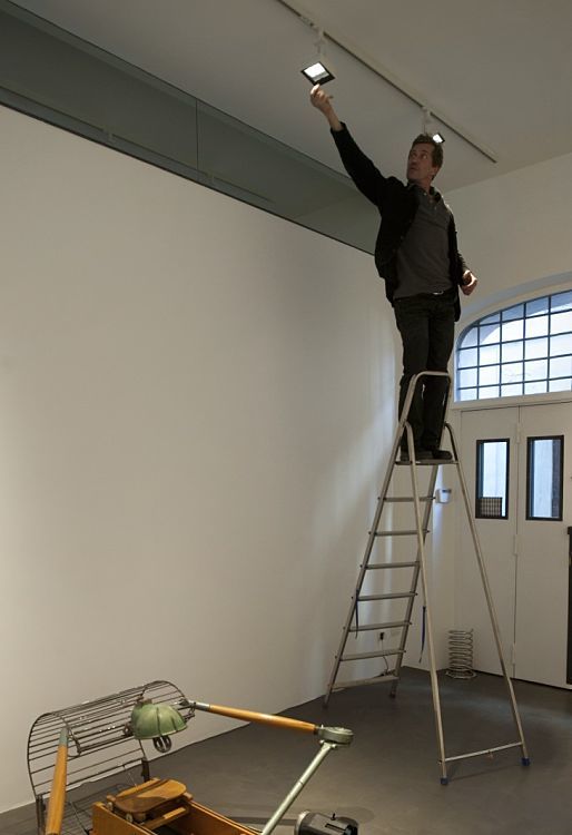 Man adjusts a Light Board spotlight on a ladder in the Anna Marra Contemporanea Gallery.