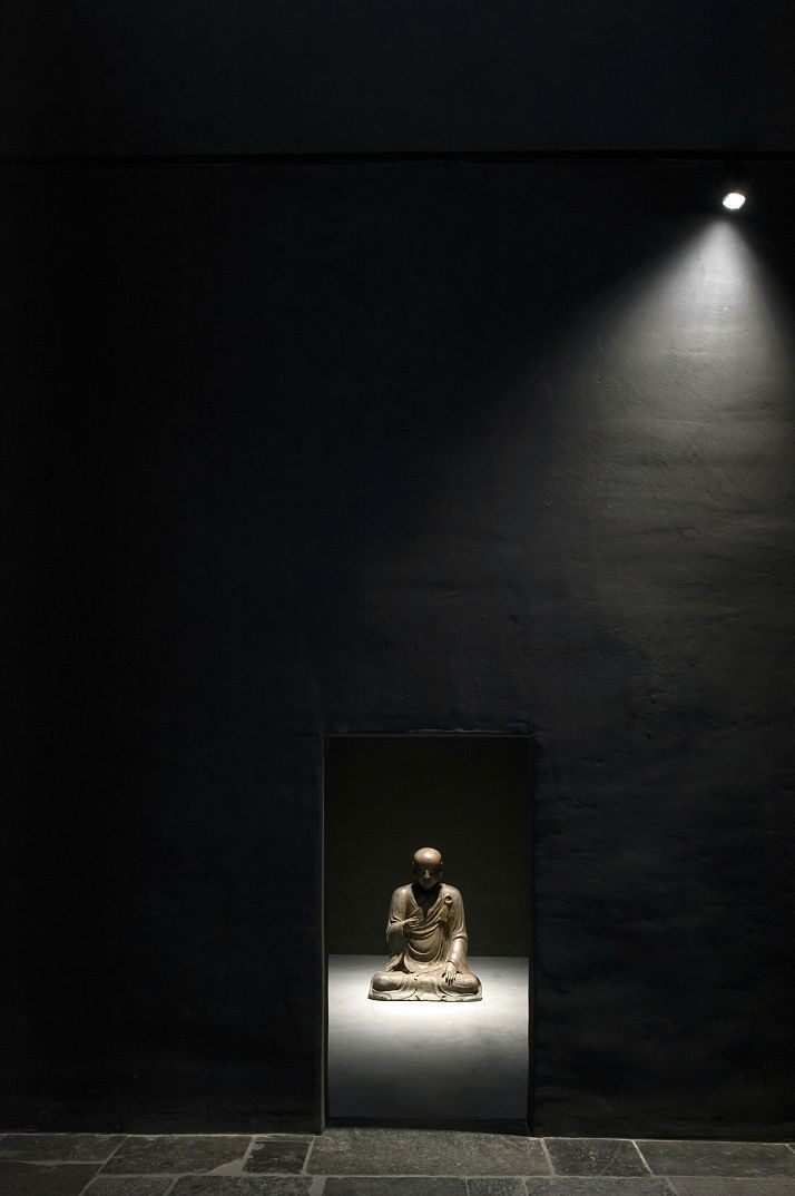 Illuminated Buddha statue in Axel Vervoordt Gallery, highlighted by ERCO LED spotlights.