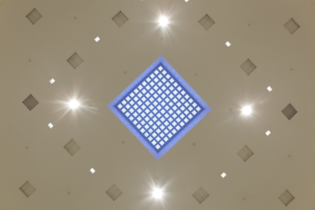 Ceiling detail of Bibliothek 21 featuring square ERCO Quintessence recessed lights and a blue skylight.