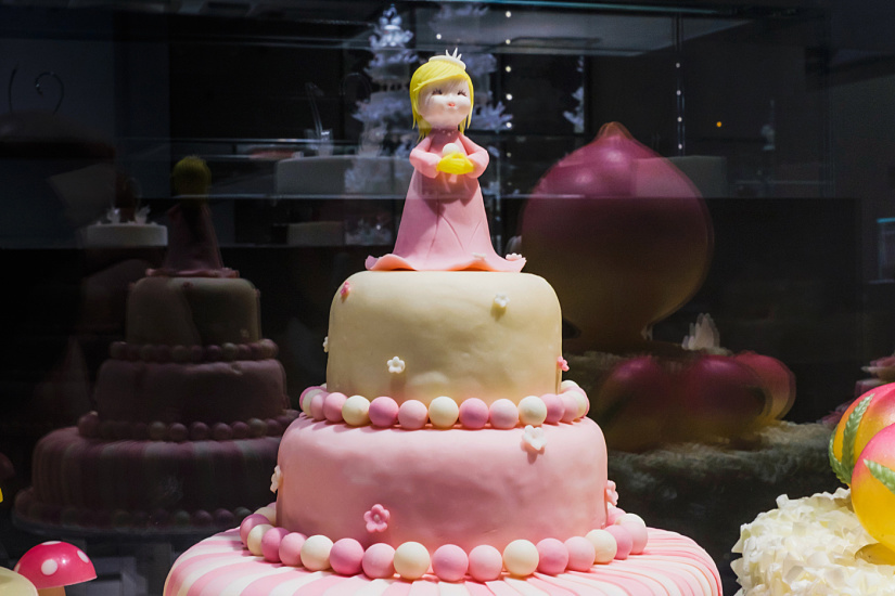 Decorated cake with princess figure at Black Swan patisserie, illuminated by ERCO Optec spotlights.