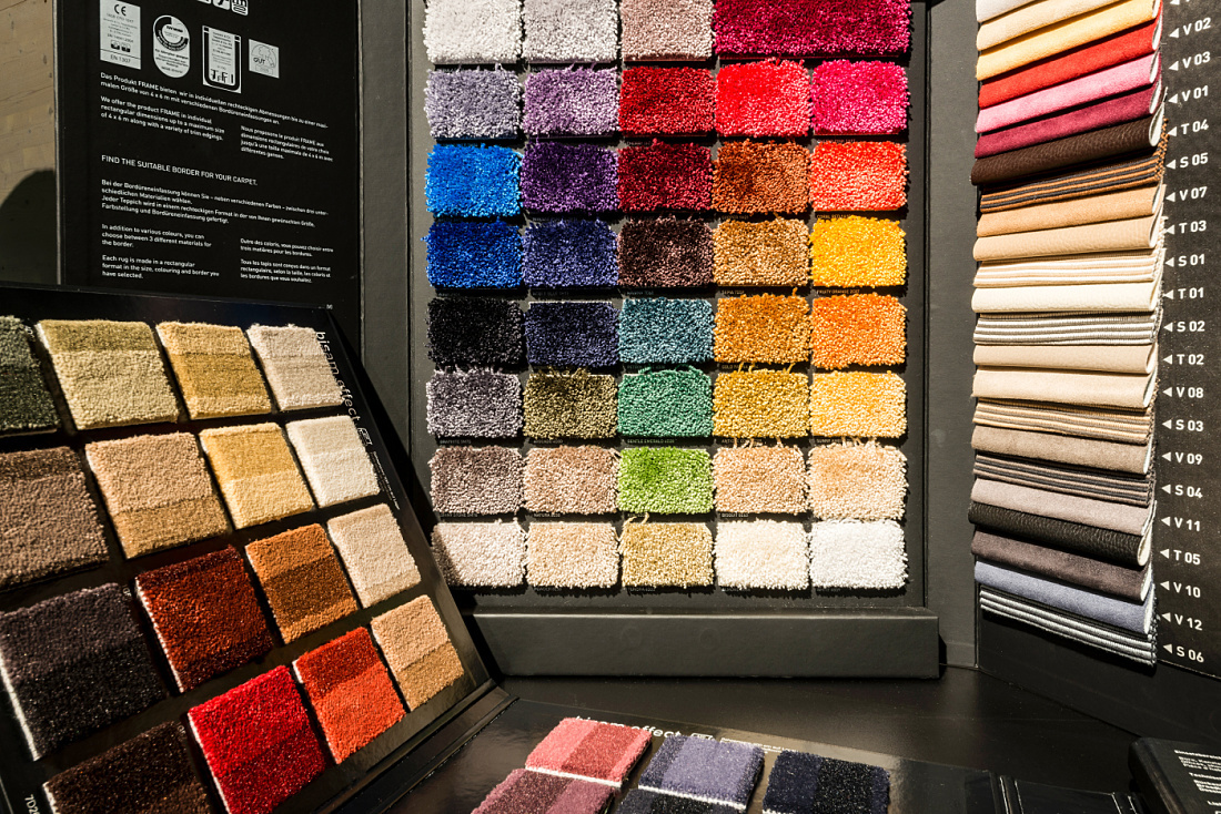 Blaha showroom display of colorful carpet and fabric samples for office furniture, illuminated by LED lighting.