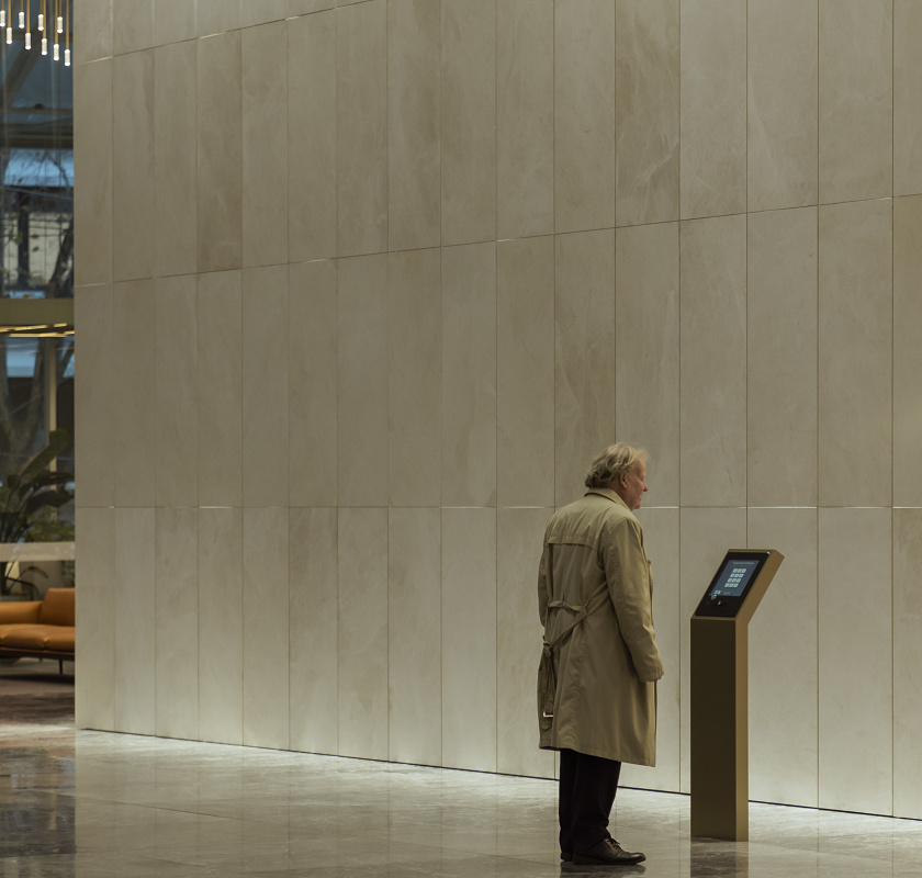 Man using interactive display in Bourke Place Lobby, illuminated by ERCO Gimbal recessed spotlights.