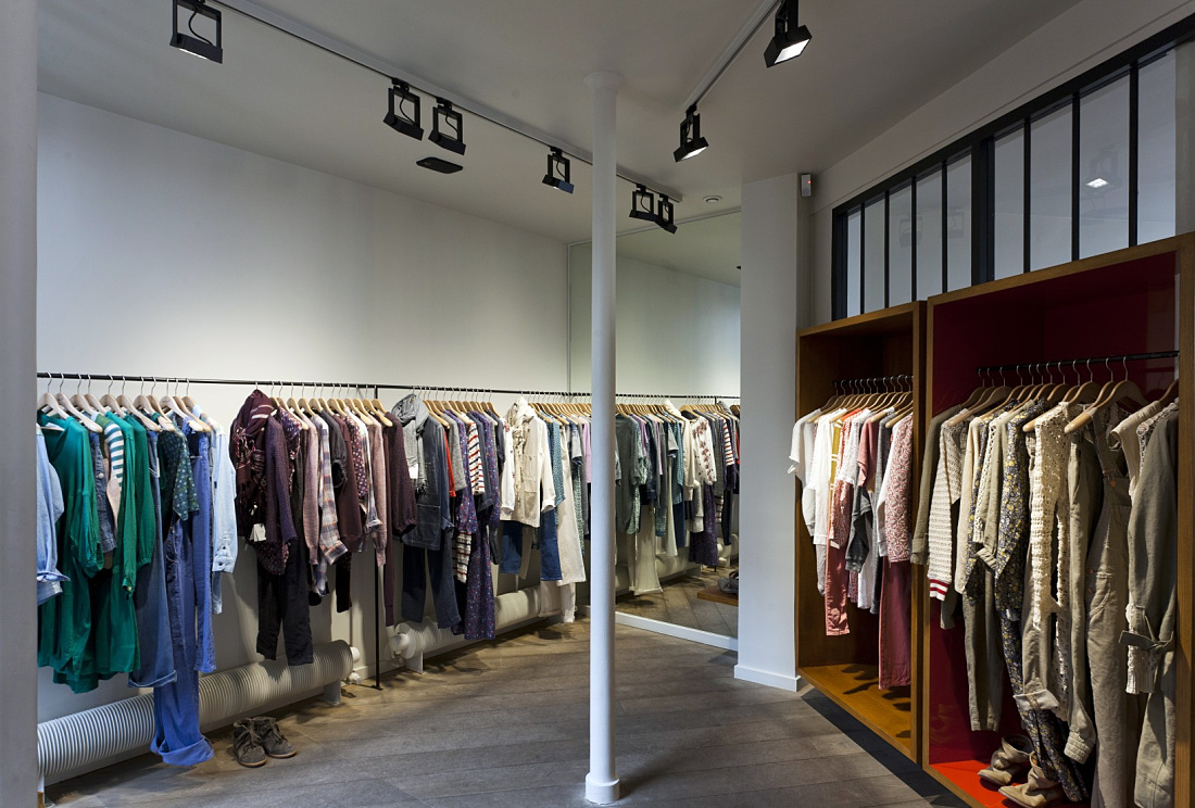 Paris boutique featuring track lighting by ERCO, illuminating clothing racks for dynamic product display.