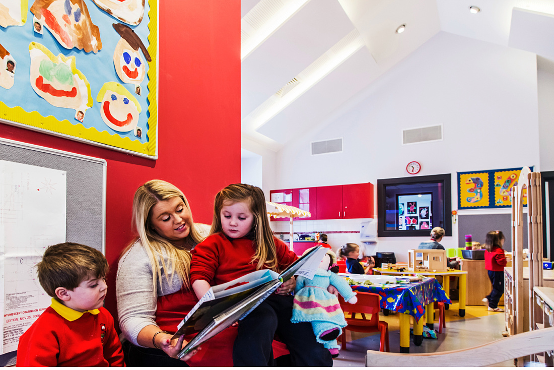 Teacher reading to children at Brontë Nursery, illuminated by ERCO LED lighting.