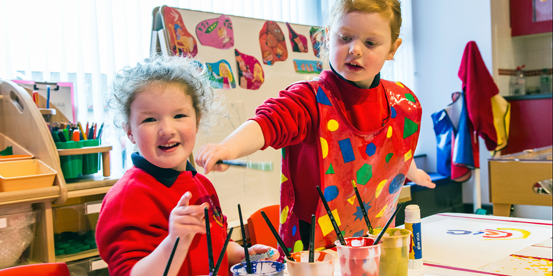Children painting with brushes at Brontë Nursery, Rathfriland.