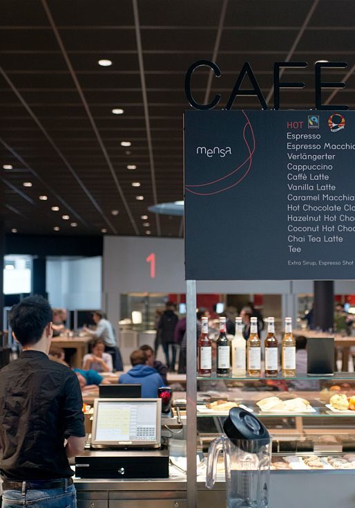 Cafeteria at Vienna University with menu and hot food, illuminated by ERCO LED lighting.
