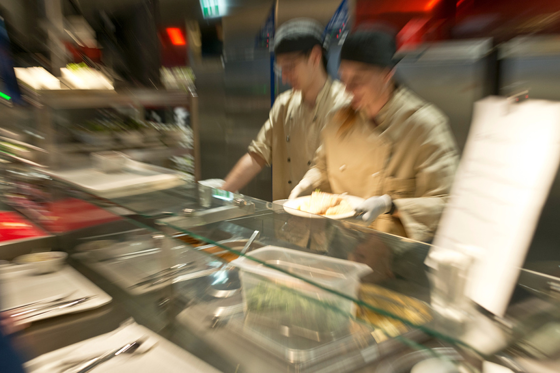 Food service in the Vienna University of Economics cafeteria with warm white lighting.