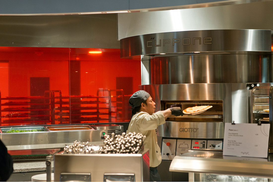 A chef places a pizza into a Cuppone pizza oven in the WU Vienna cafeteria.