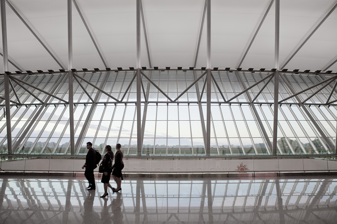 Carrasco International Airport terminal: Travelers under curved roof, illuminated by ERCO lighting.
