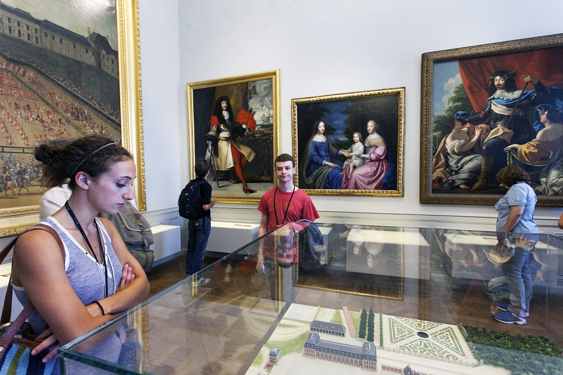 Visitors view paintings and a model of Château de Versailles, illuminated by ERCO lighting.