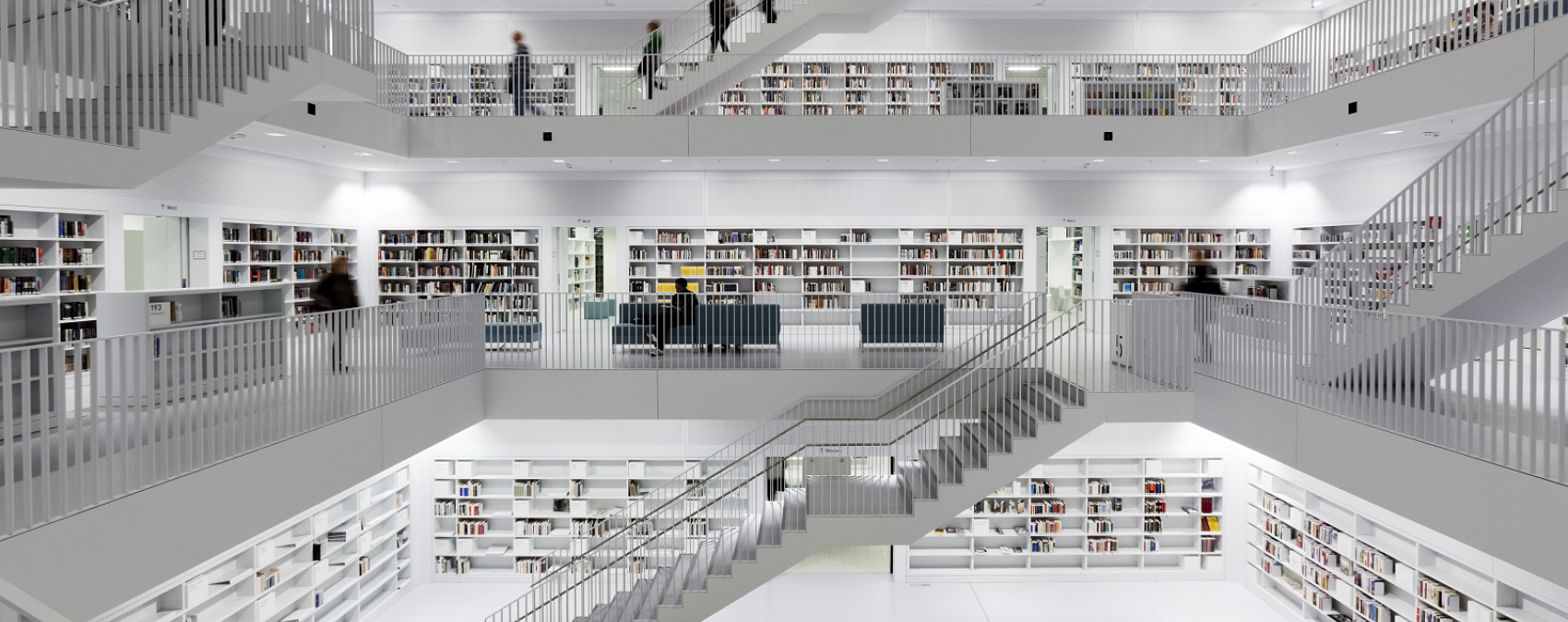 Multi-story library with stairs and shelves, illuminated by ERCO lighting.