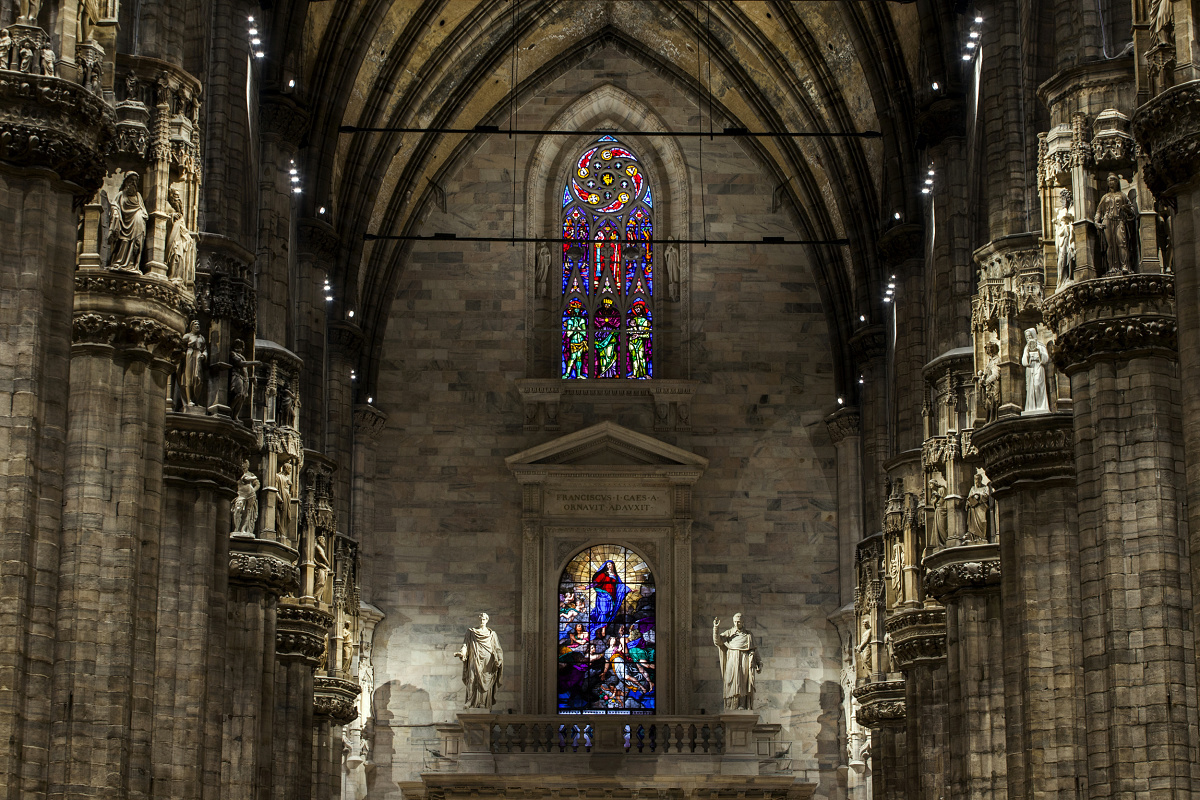 Milan Cathedral interior featuring stained glass, showcasing contrast in lighting.