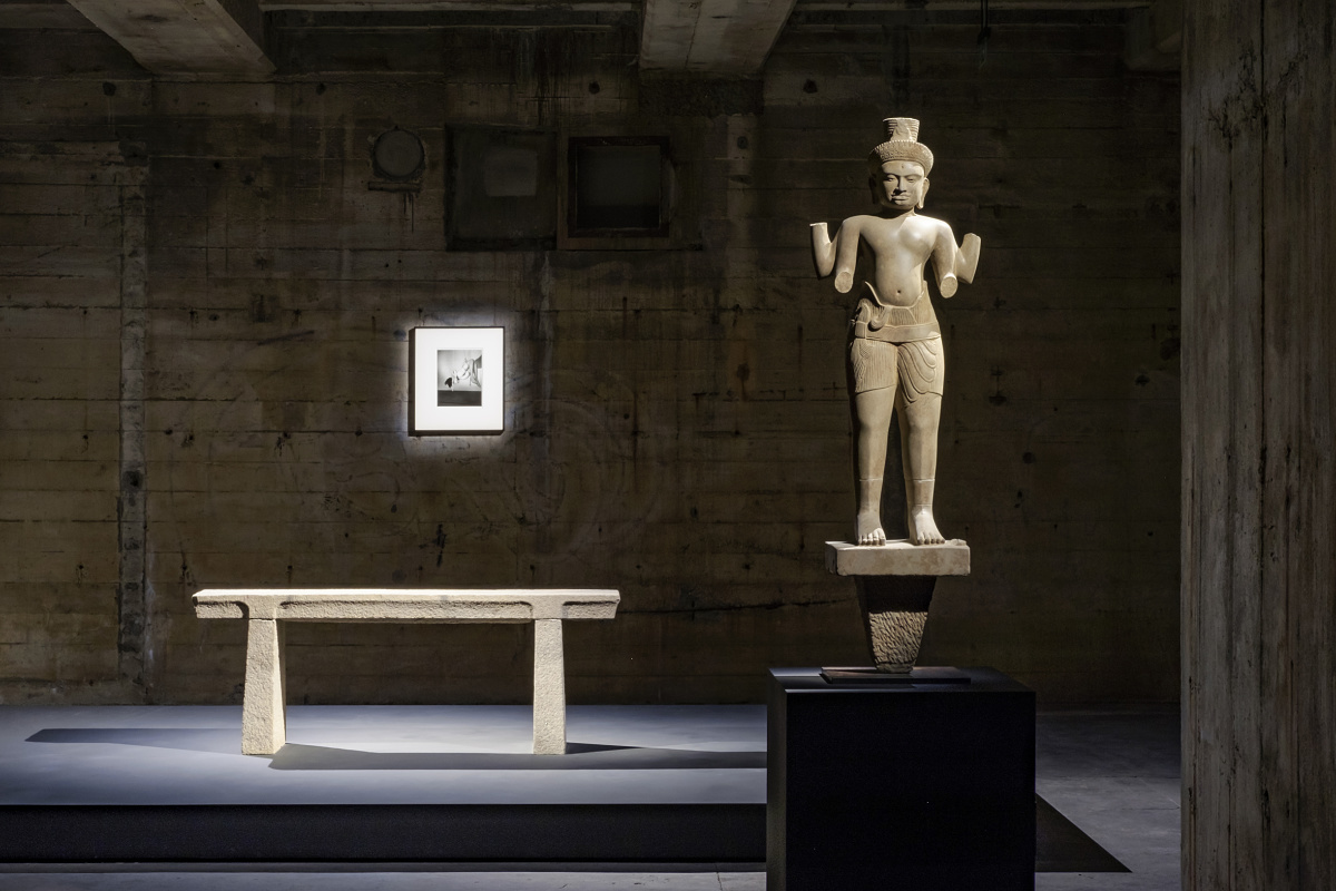 Illuminated sculpture and bench in a dark room, highlighting contrasts.