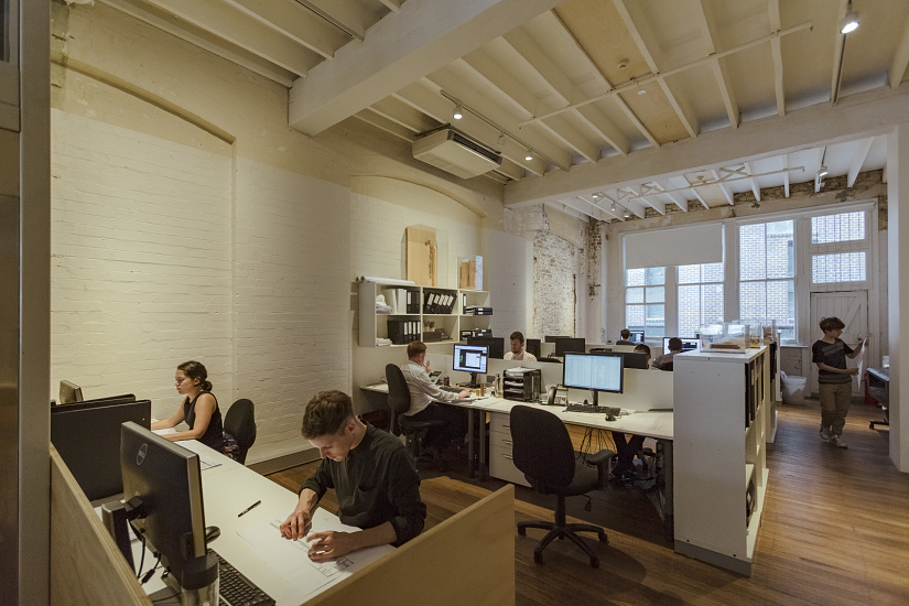 Illuminazione ERCO su binario elettrificato con downlight in ufficio moderno, per un'illuminazione flessibile.