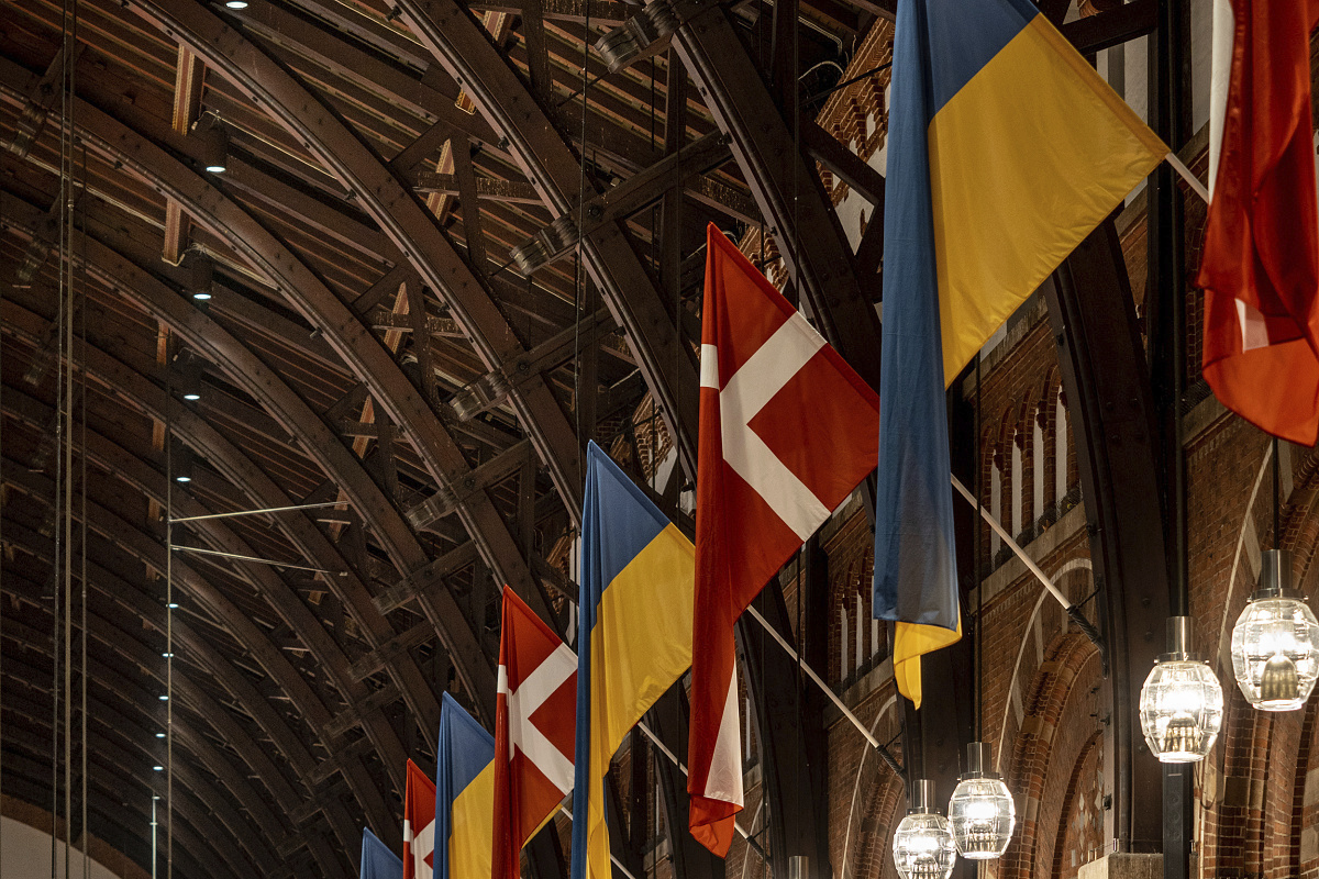 Danish and Ukrainian flags under ERCO LED lighting at Copenhagen Central Station.