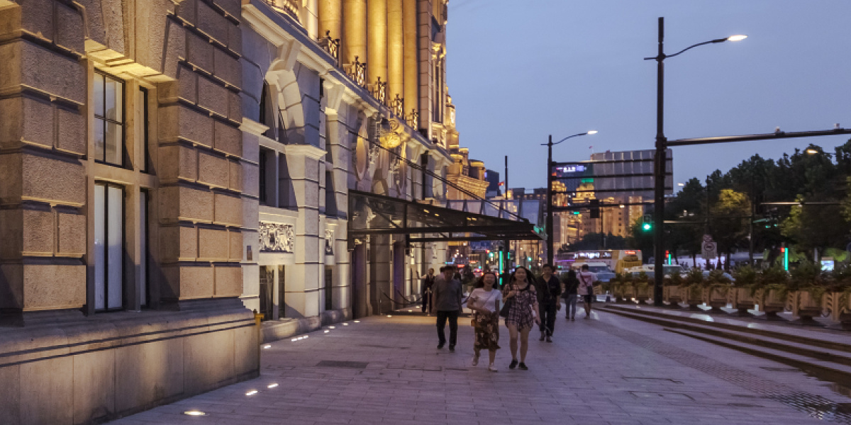 Illuminated station facade with pedestrians using safe pathway lighting for orientation.