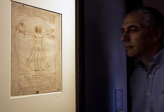 Viewer in front of Da Vincis Vitruvian Man, a sensitive artwork under LED lighting.