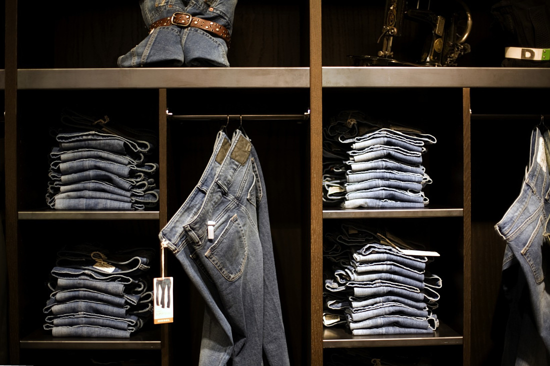 Diesel jeans displayed on shelves and hanging, part of modern store lighting at Milans flagship store.