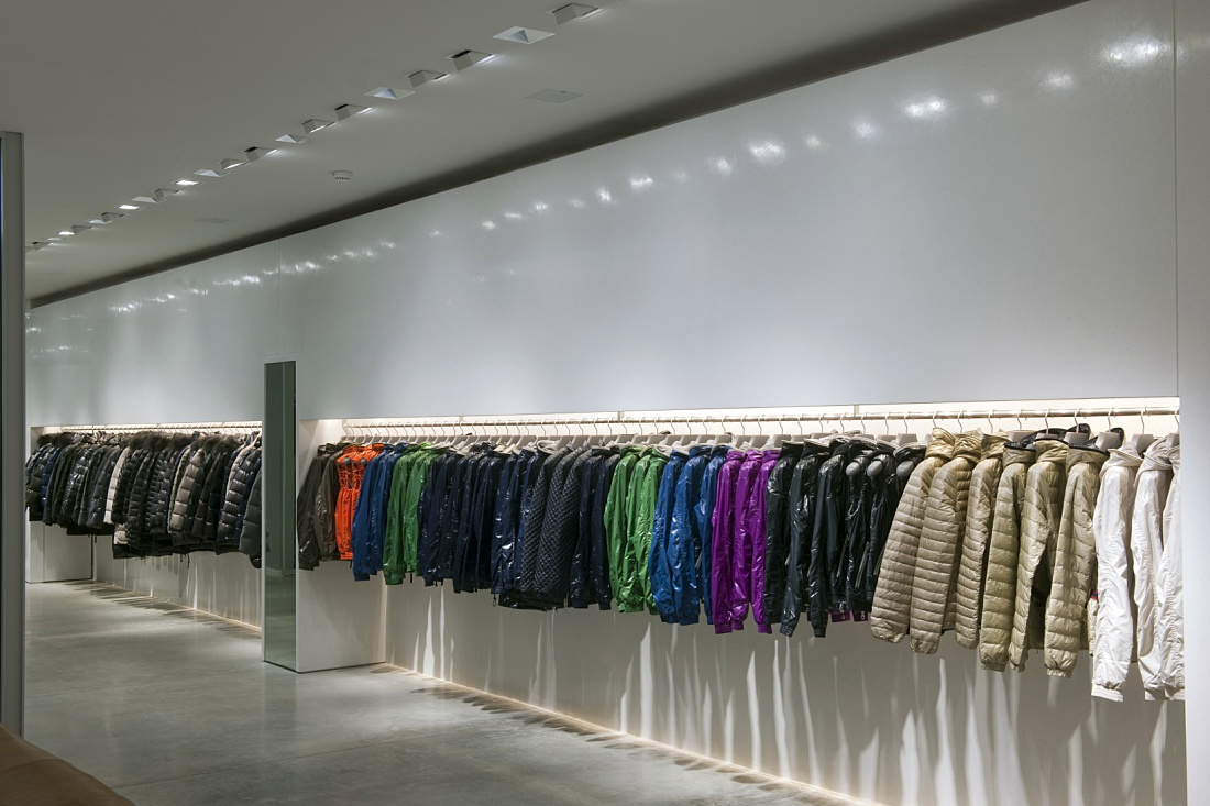 Duvetica showroom featuring fashionable down jackets illuminated by ERCO LED lighting in Tadao Andos minimalist space.