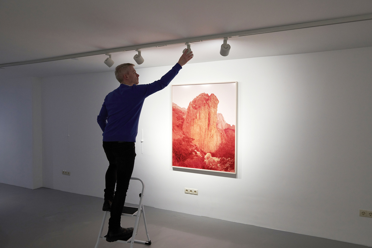 A man adjusts an ERCO Parscan InTrack spotlight in the Enari Gallery to optimally illuminate an artwork.