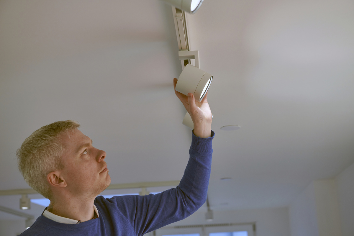 A man adjusts an ERCO Parscan InTrack spotlight in the Enari Gallery, Amsterdam.