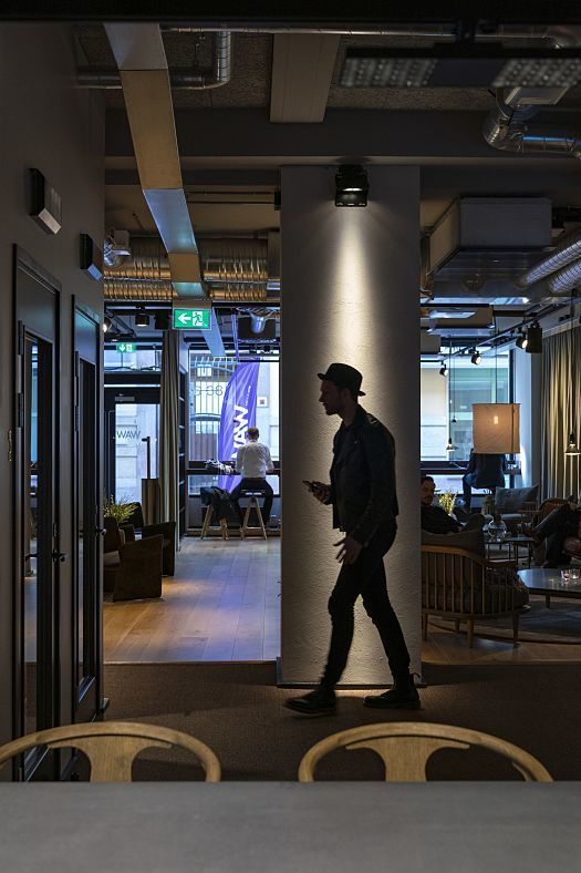 Man walks through Fabege WAW office, illuminated by ERCO LED downlights for flexible workspaces.