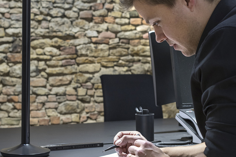 Man working in office with ERCO Lucy task light for ergonomic illumination.