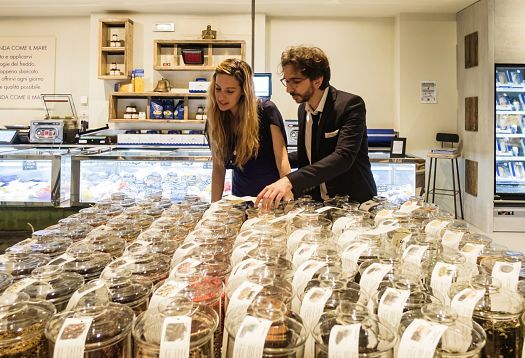 Customers select gourmet food at Fiorital delicatessen, Padua, illuminated by ERCO LED lights.
