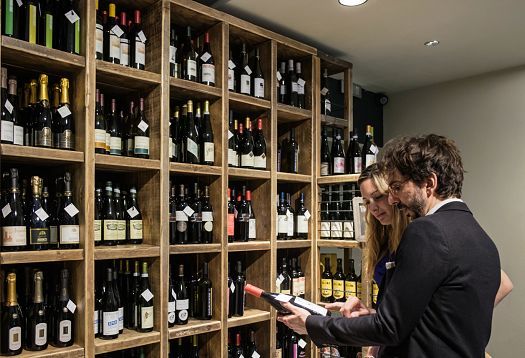 Customers selecting wine at Fiorital delicatessen, illuminated by ERCO LED lighting.