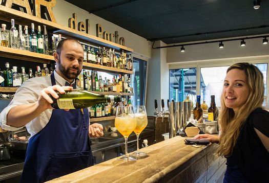 Bartender preparing drinks at Fiorital delicatessen in Padua, illuminated by ERCO LED lighting.