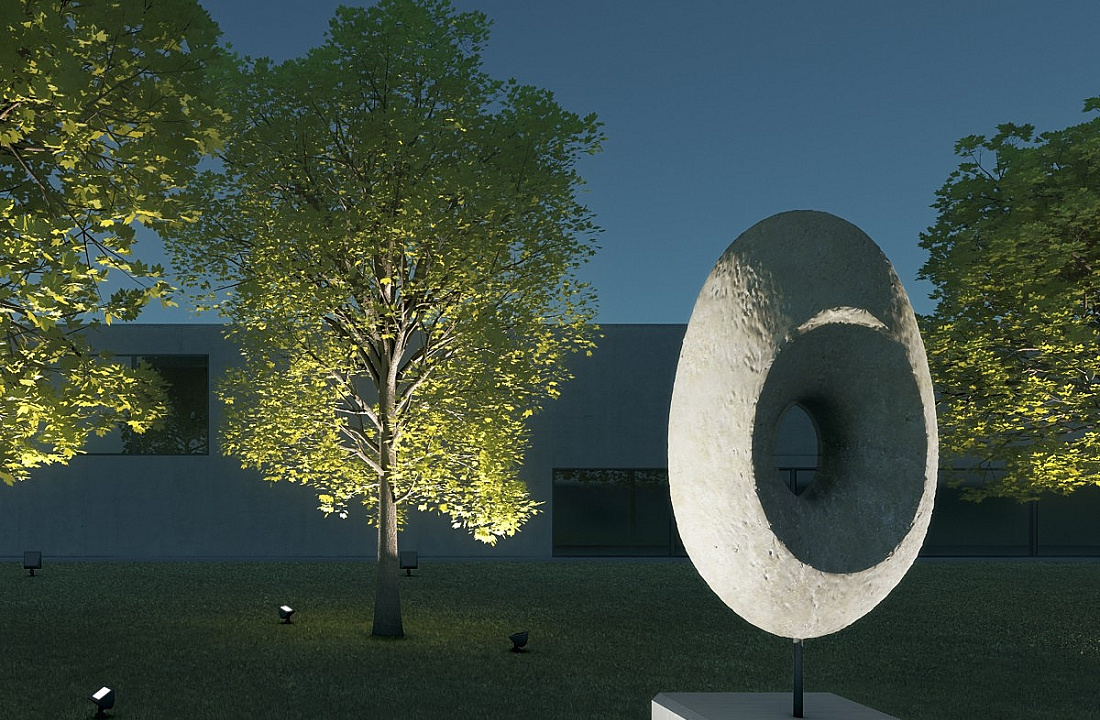 Illuminated sculpture in the foreground, trees in the middle ground, and facade in the background.