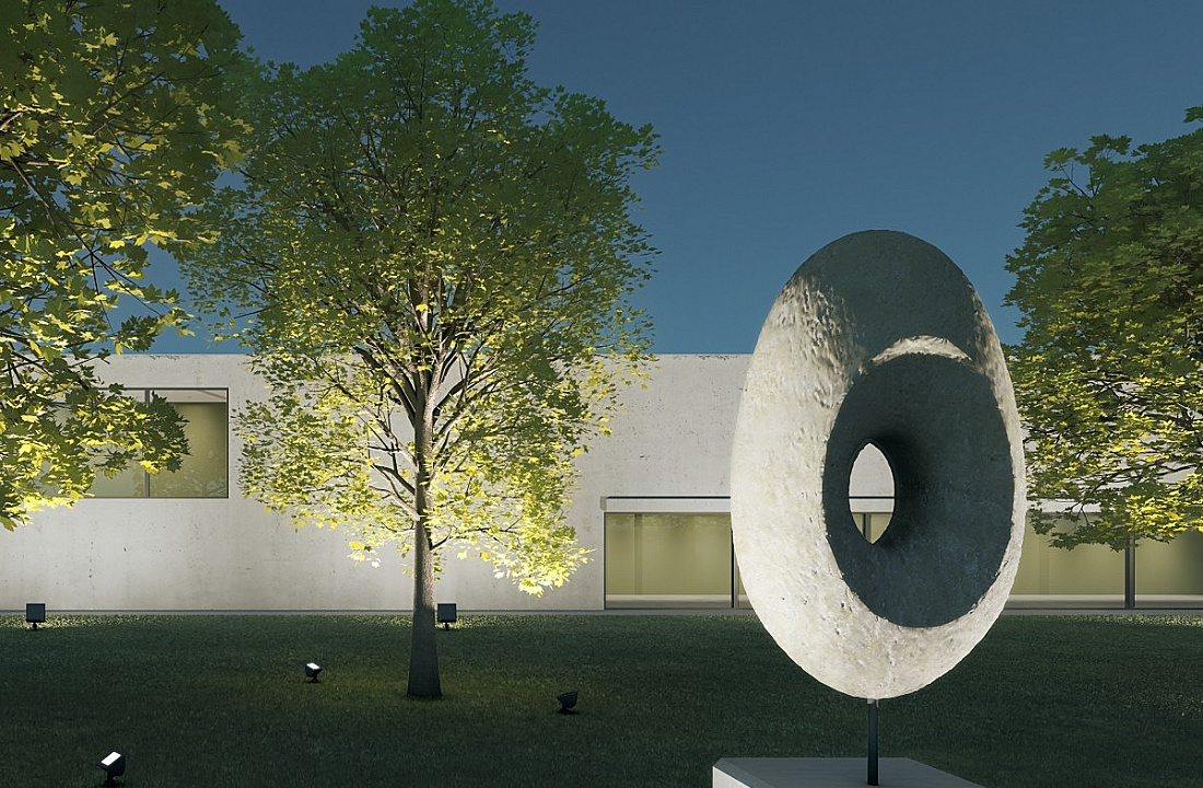 Illuminated sculpture in the foreground, trees in the middle ground, and facade in the background.