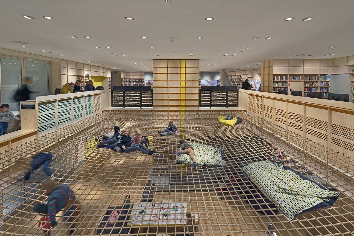 Children relax on a net under ERCO LED lighting in the Forum Groningen.