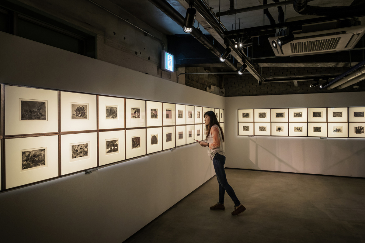 Woman views art illuminated by ERCO contour spotlights in a gallery setting.