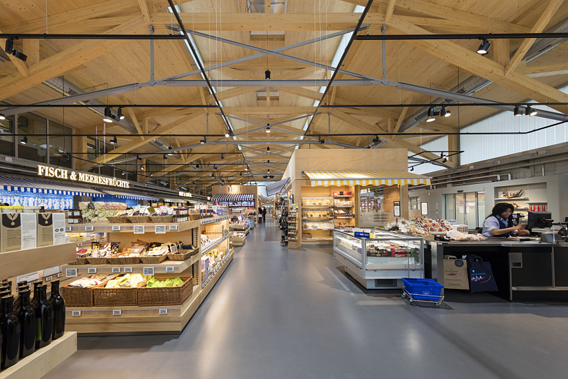 FrischeParadies Stuttgart store featuring ERCO LED spotlights accentuating gourmet foods under timber roof.