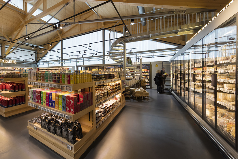 FrischeParadies Stuttgart: ERCO LED spotlights accent gourmet foods in a modern market with wood construction.