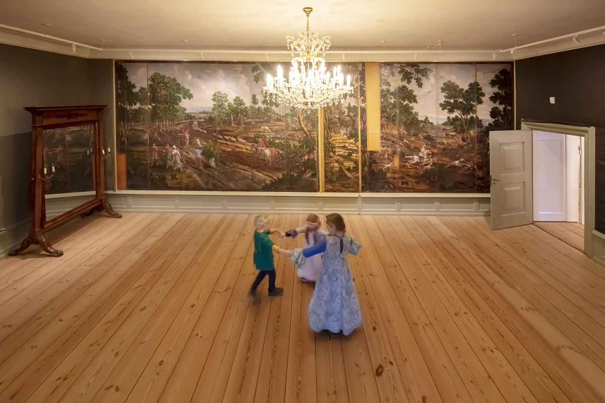 Glücksburg Castle interior with Eclipse spotlights illuminating historic tapestries as children play.