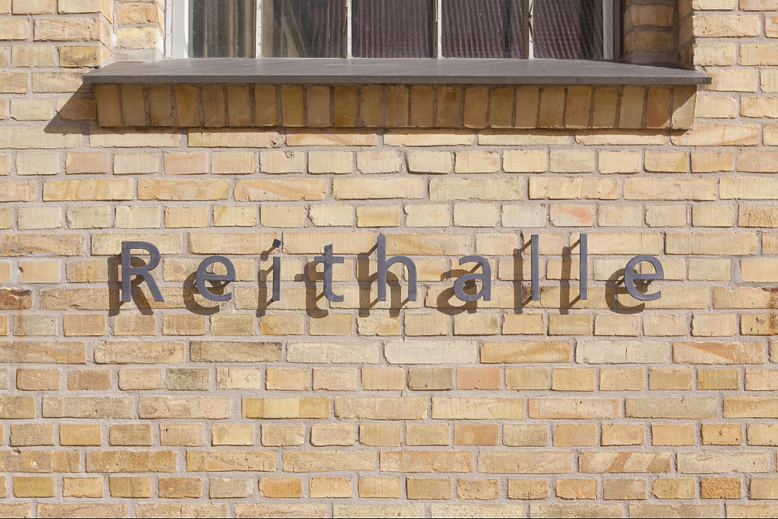 Gottorf Palace Riding Hall facade with lettering, illuminated by ERCO Light Board spotlights.