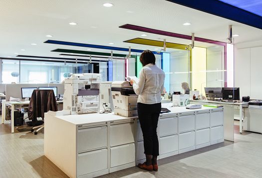Woman using a copier in an office space with ERCO LED lighting at Graficas Varias, Barcelona.