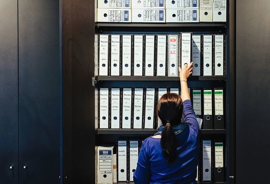 Woman reaching for files in Graficas Varias office, lit by ERCO LEDs for ergonomic workplace lighting.