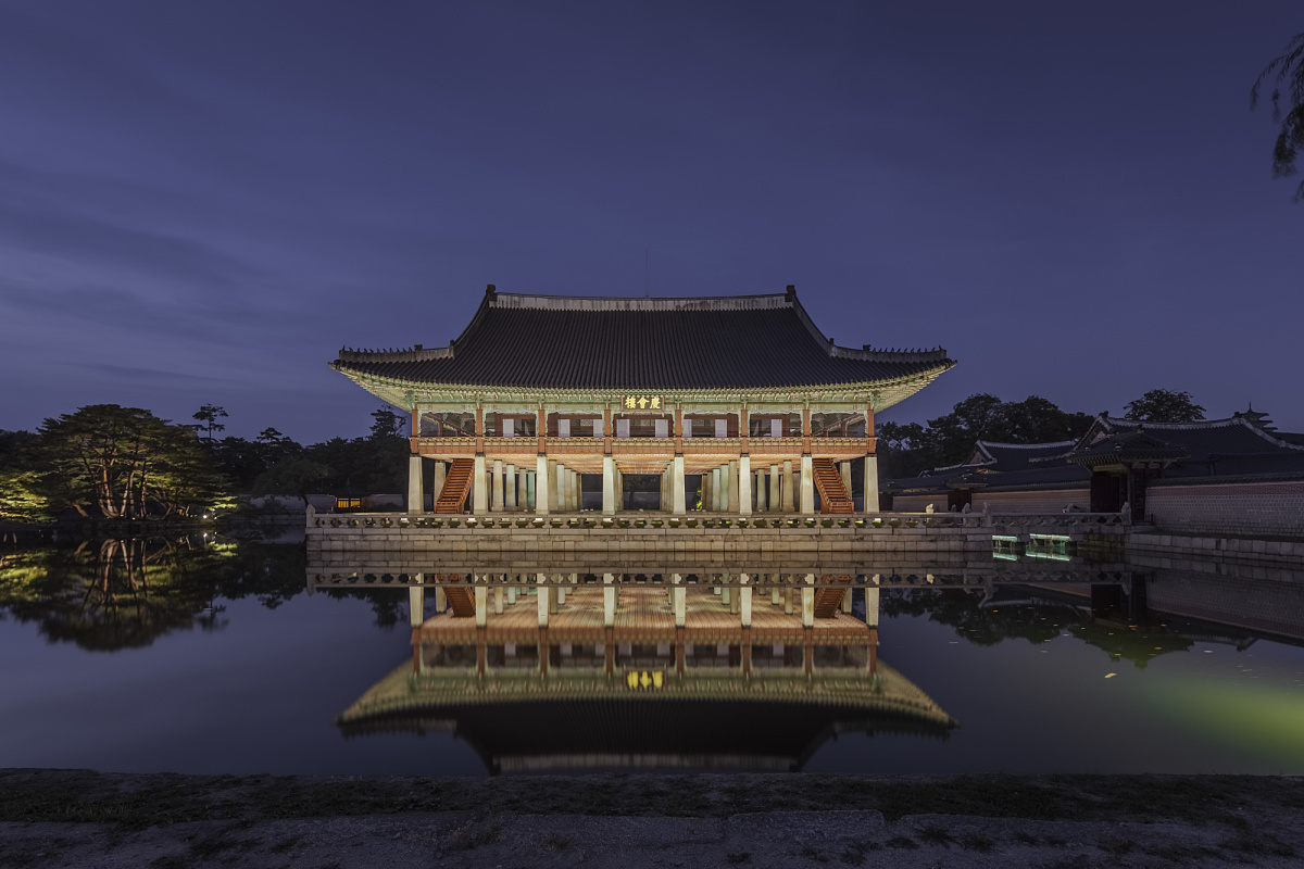 Gyeongbokgung Palace in Seoul, illuminated by ERCO, showcasing pagoda-style architecture at night.