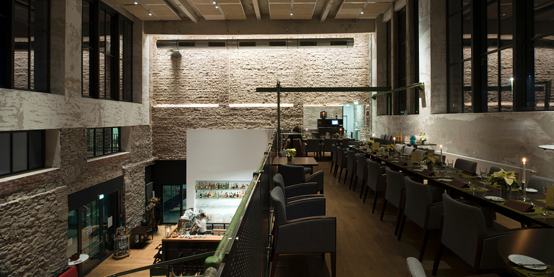 Halle 32 restaurant in Gummersbach, featuring ERCO Optec spotlights highlighting industrial architecture.
