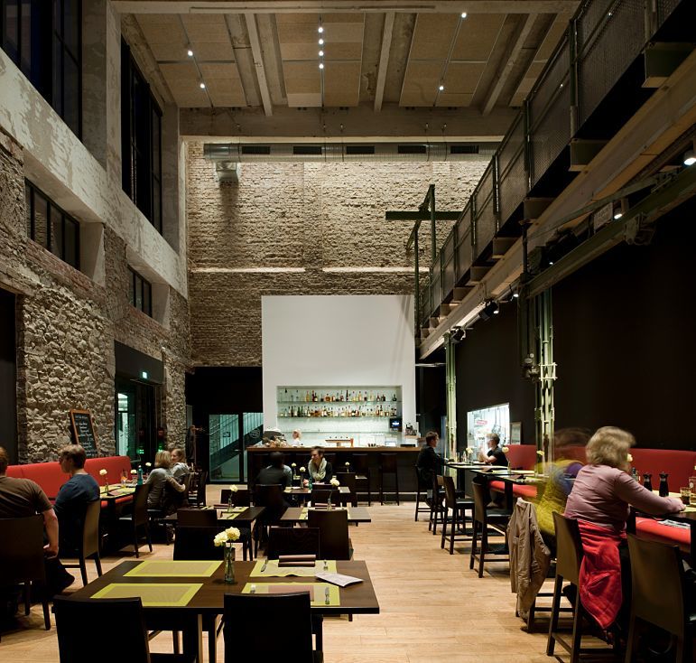 Interior of Halle 32 restaurant in Gummersbach, featuring ERCO Optec spotlights highlighting industrial architecture.