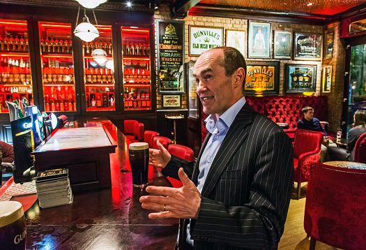 Man at the Harp Bar, Belfast, with a Guinness. LED lighting accentuates the Victorian decor.