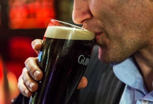 A man drinking a Guinness stout at the Harp Bar in Belfast.