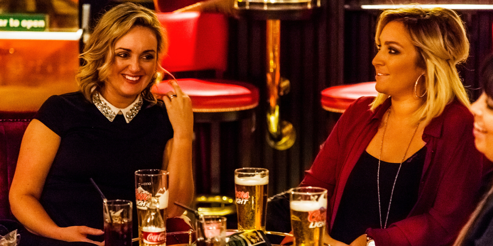 Women enjoying drinks at the atmospheric Harp Bar, Belfast, illuminated with ERCO LED lighting.
